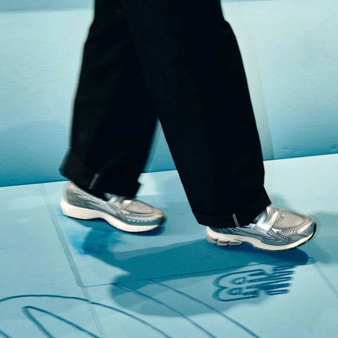New Balance 1906L Metallic Silver U1906LAE på fødder med sorte bukser